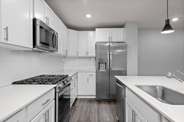 kitchen with a sink, white cabinets, stainless steel appliances, and dark wood-style floors