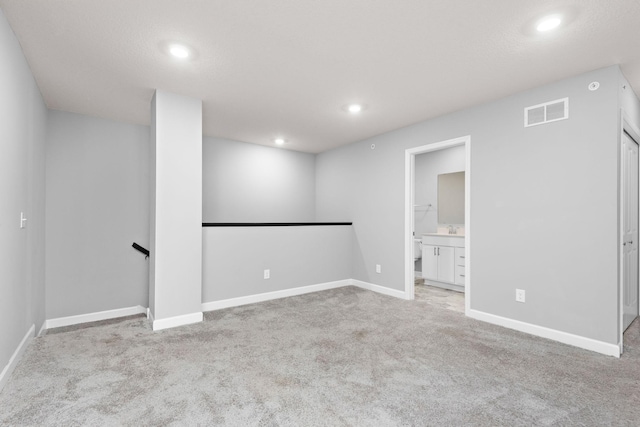 below grade area featuring a sink, carpet, recessed lighting, baseboards, and visible vents