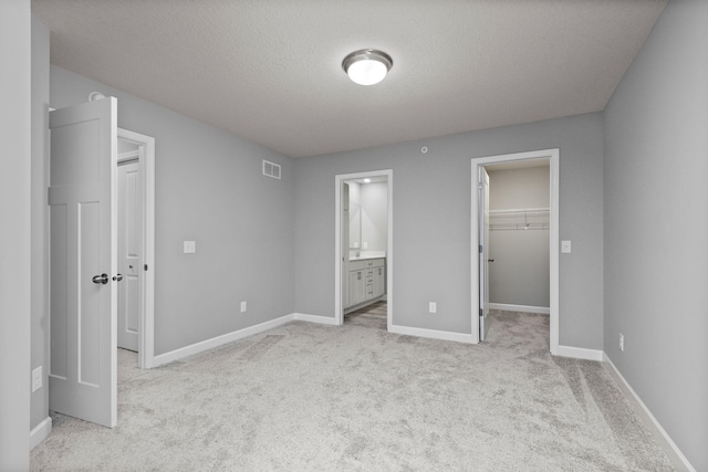 unfurnished bedroom featuring visible vents, baseboards, a closet, a spacious closet, and light carpet