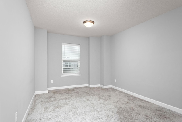 carpeted empty room featuring a textured ceiling and baseboards