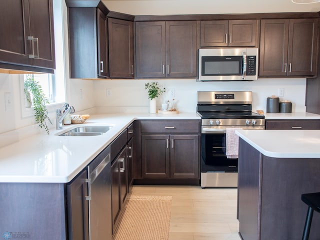 6735 Meadow View Dr S, Fargo, ND 58104 - kitchen featuring dark brown cabinets, light countertops, a sink, light wood finished floors, and appliances with stainless steel finishes