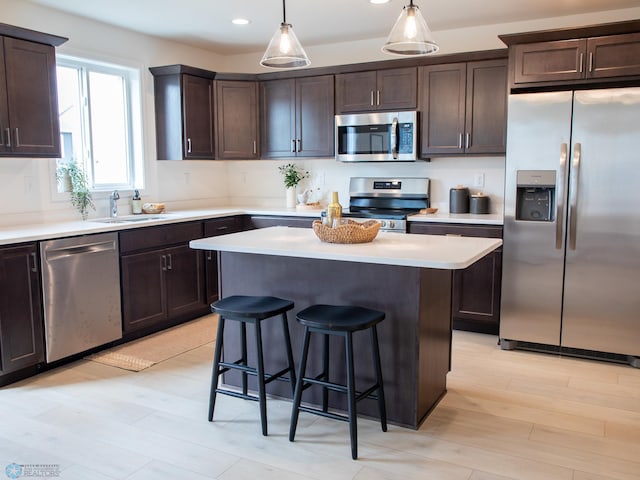 6735 Meadow View Dr S, Fargo, ND 58104 - kitchen featuring a kitchen breakfast bar, a kitchen island, appliances with stainless steel finishes, dark brown cabinets, and a sink