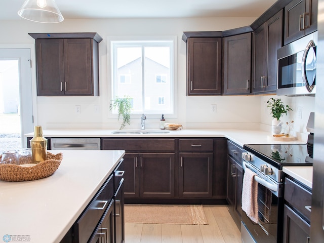 6735 Meadow View Dr S, Fargo, ND 58104 - kitchen with dark brown cabinets, a sink, light wood finished floors, light countertops, and stainless steel appliances
