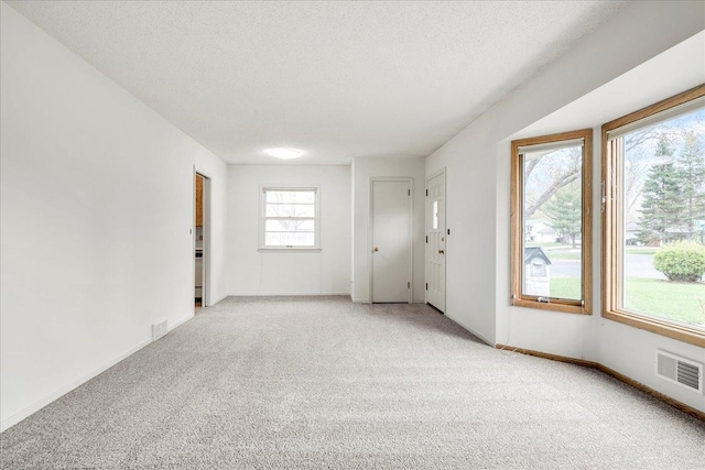 empty room featuring light carpet, baseboards, and visible vents