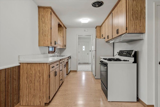 kitchen with under cabinet range hood, dishwasher, light wood finished floors, light countertops, and gas range gas stove
