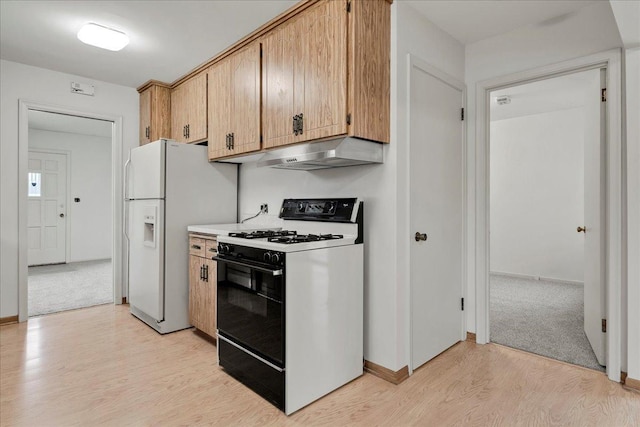 kitchen featuring under cabinet range hood, light wood-style flooring, baseboards, and range with gas stovetop