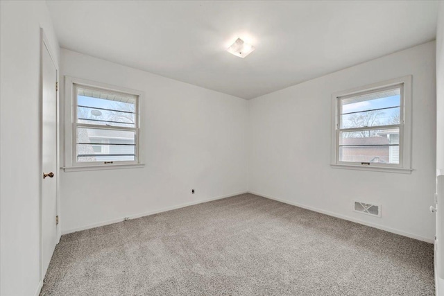 carpeted spare room featuring visible vents and baseboards