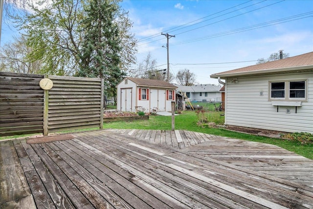 wooden deck featuring a lawn, fence, a shed, and an outbuilding