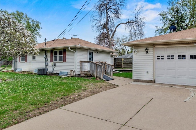 view of side of property with driveway, a garage, central AC, and a lawn