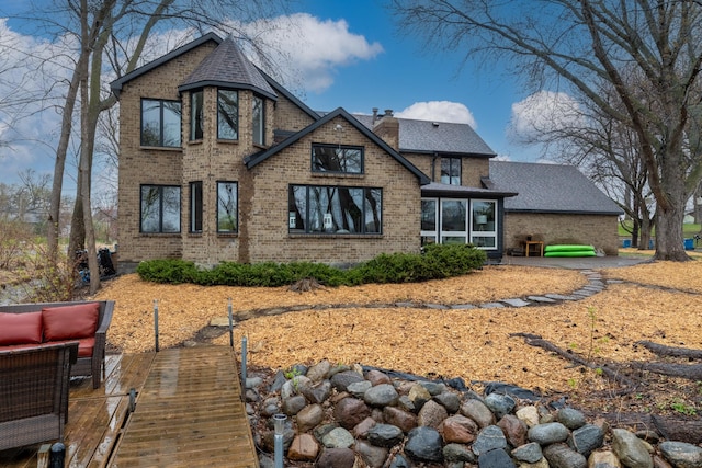 211 Peninsula Rd, Medicine Lake, MN 55441 - back of house with brick siding, a chimney, and roof with shingles