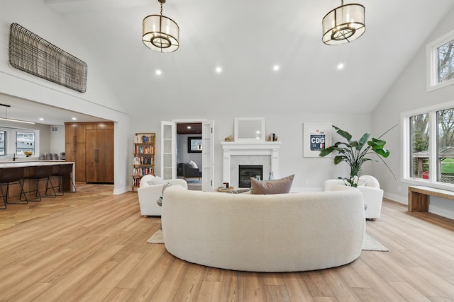 211 Peninsula Rd, Medicine Lake, MN 55441 - living area with high vaulted ceiling, a tiled fireplace, light wood-style flooring, baseboards, and recessed lighting