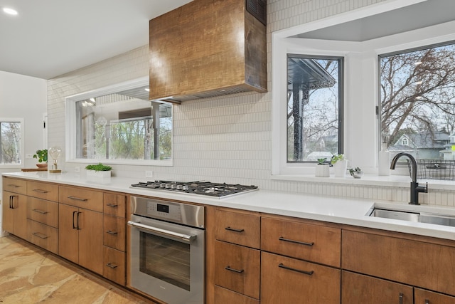 211 Peninsula Rd, Medicine Lake, MN 55441 - kitchen with stainless steel appliances, wall chimney exhaust hood, light countertops, decorative backsplash, and a sink