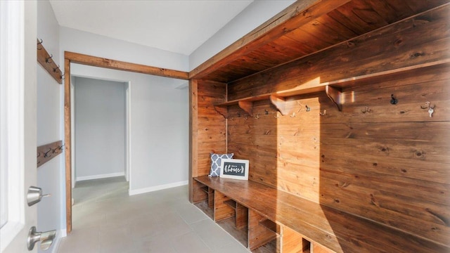 mudroom featuring tile patterned floors, wooden walls, and baseboards