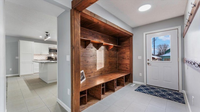 mudroom featuring baseboards, a textured ceiling, and light tile patterned floors