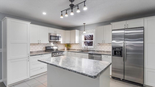 kitchen with white cabinets, stainless steel appliances, a sink, a center island, and decorative backsplash