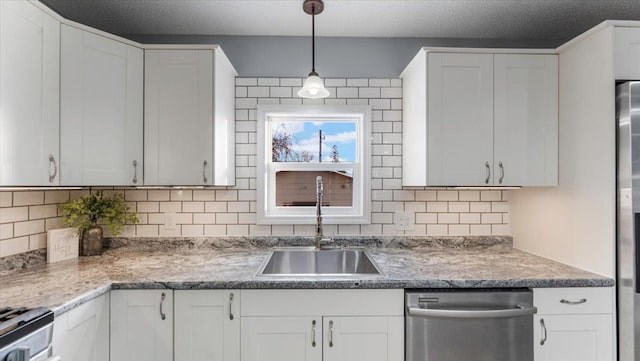 kitchen featuring stainless steel appliances, a sink, backsplash, white cabinetry, and pendant lighting