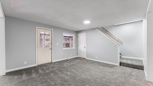 below grade area with dark colored carpet, baseboards, a textured ceiling, and stairs