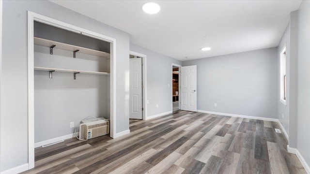 unfurnished bedroom with recessed lighting, wood finished floors, a closet, and baseboards