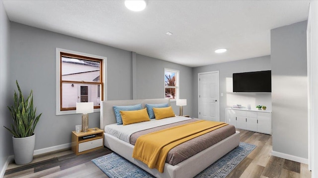 bedroom with recessed lighting, wood finished floors, and baseboards