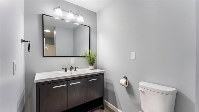 bathroom with baseboards, vanity, and toilet