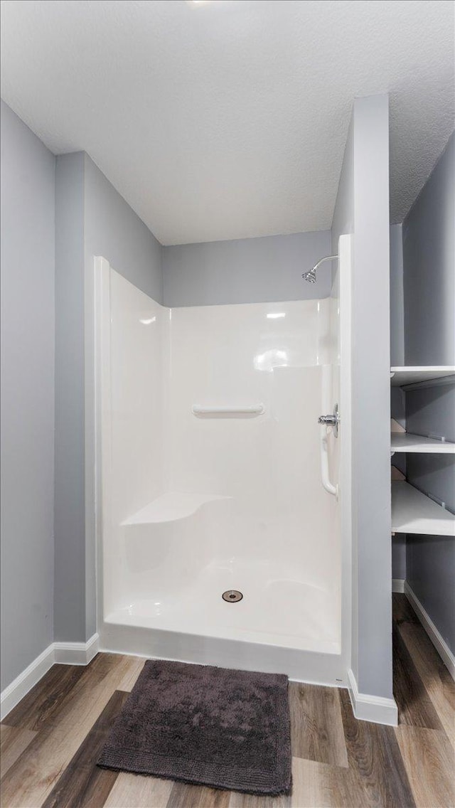 full bath with baseboards, wood finished floors, and a shower