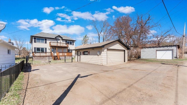 view of front of property featuring fence, a wooden deck, an outdoor structure, and a garage
