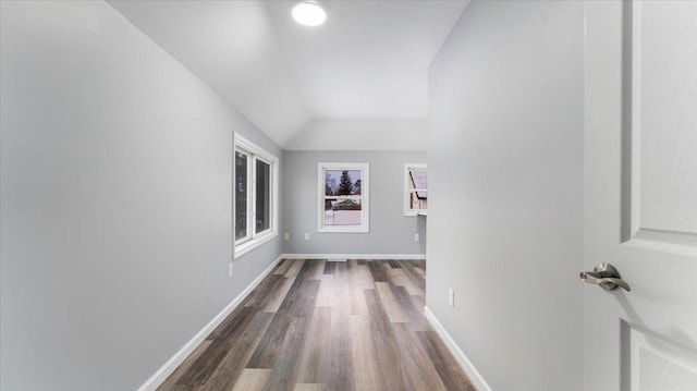 hall featuring baseboards, vaulted ceiling, and dark wood-style floors