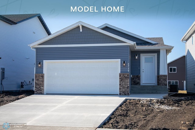 craftsman-style house with an attached garage, central AC, brick siding, and concrete driveway