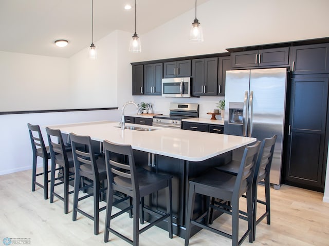 kitchen with light wood-style floors, a sink, appliances with stainless steel finishes, and a kitchen breakfast bar