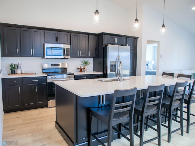 kitchen featuring light countertops, pendant lighting, appliances with stainless steel finishes, and high vaulted ceiling