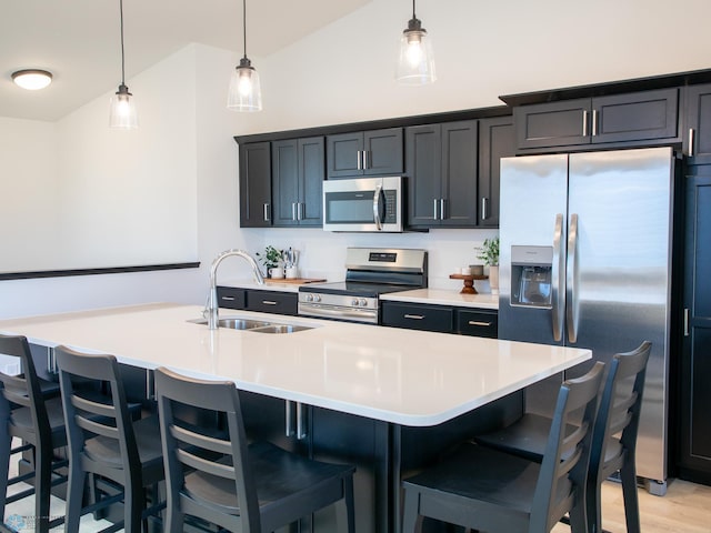kitchen featuring a kitchen bar, appliances with stainless steel finishes, vaulted ceiling, a sink, and light countertops