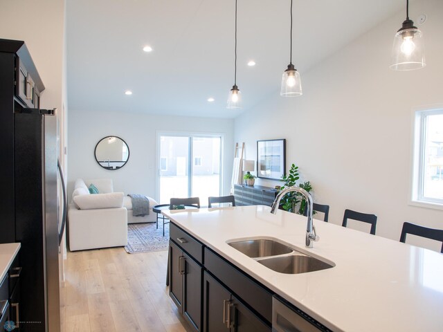 kitchen featuring a kitchen bar, a sink, freestanding refrigerator, light wood finished floors, and open floor plan