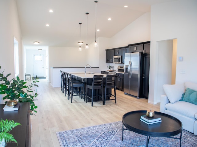 living area featuring recessed lighting, high vaulted ceiling, baseboards, and light wood finished floors