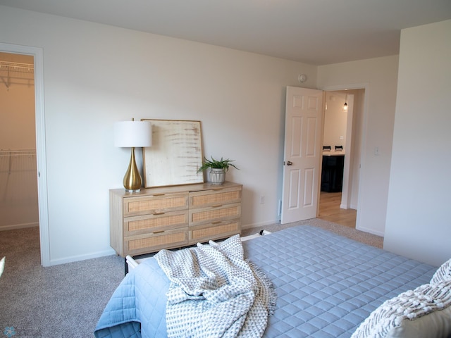 carpeted bedroom featuring baseboards, a spacious closet, and a closet