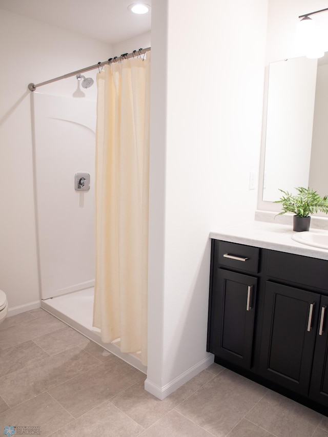 full bath with vanity, baseboards, a stall shower, and toilet