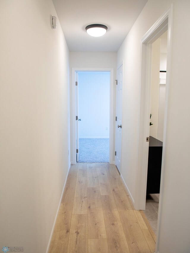 hallway featuring light wood-style floors and baseboards