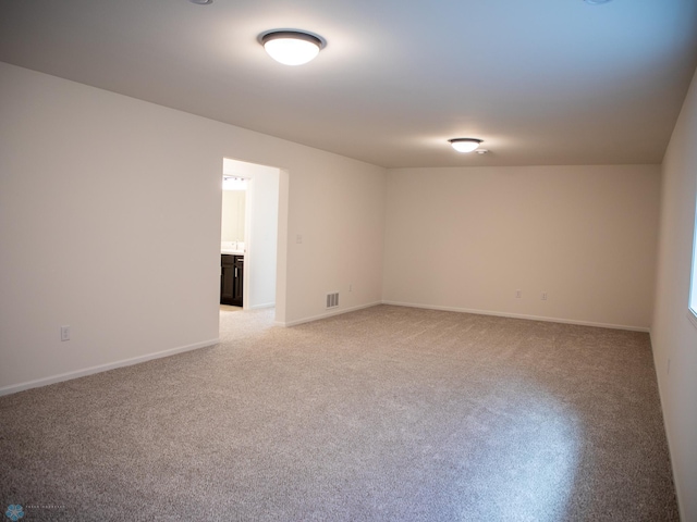spare room with visible vents, baseboards, and light carpet