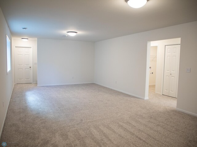 spare room with baseboards and light carpet