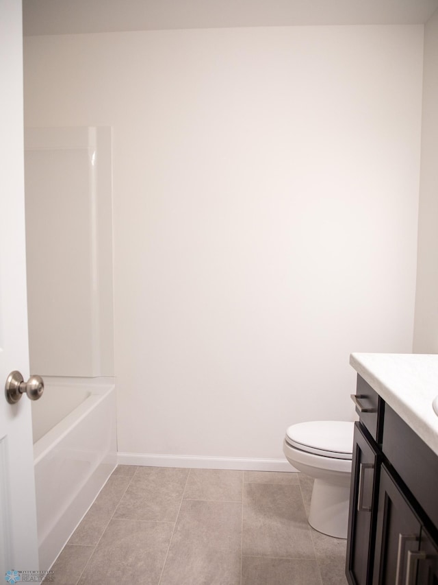 bathroom with tile patterned flooring, vanity, toilet, baseboards, and a bath