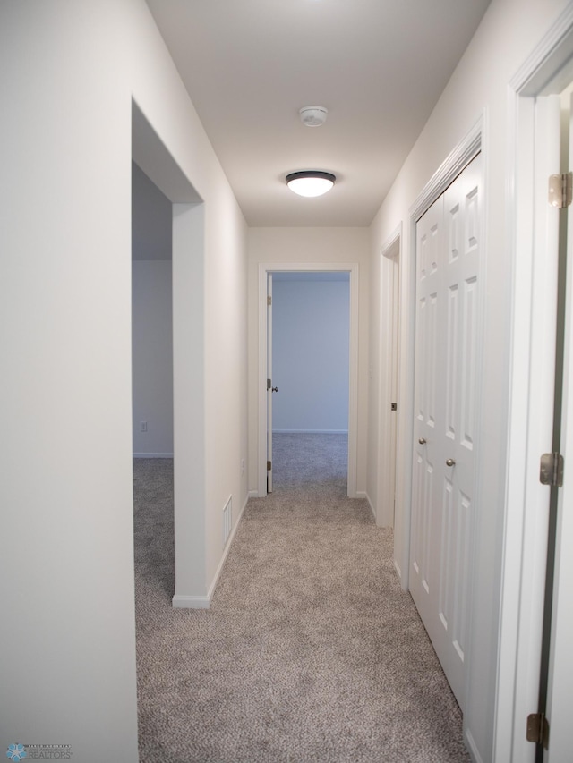 hallway featuring baseboards, carpet, and visible vents