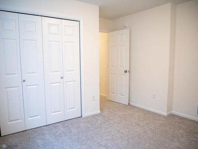 unfurnished bedroom with baseboards, visible vents, carpet, and a closet