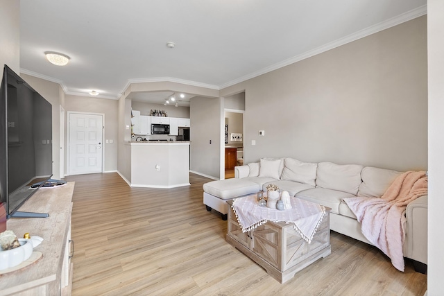 living area with crown molding, baseboards, and light wood finished floors