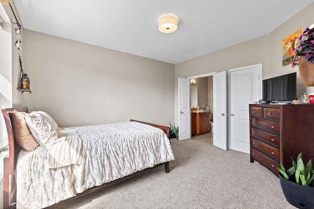 bedroom featuring ensuite bathroom and light carpet