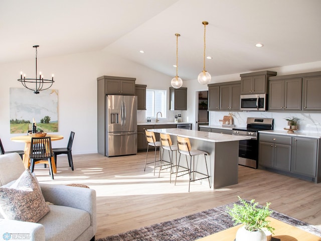 kitchen featuring an inviting chandelier, a kitchen bar, light countertops, tasteful backsplash, and stainless steel appliances