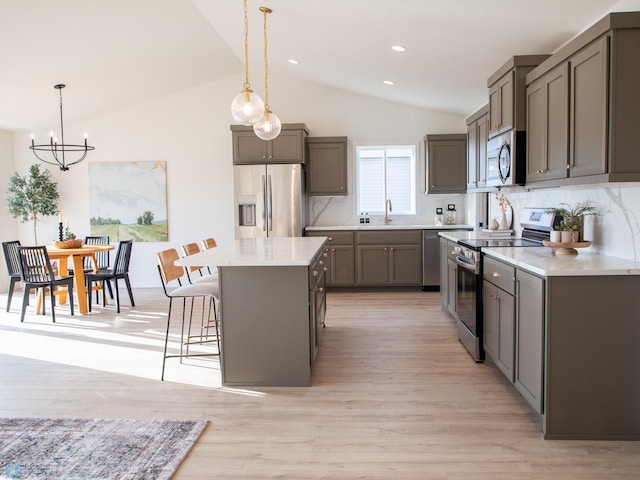 kitchen with appliances with stainless steel finishes, an inviting chandelier, decorative backsplash, vaulted ceiling, and gray cabinetry
