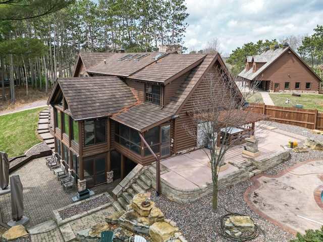 E6516 867th Ave, Colfax, WI 54730 - back of property featuring a patio, a sunroom, a fenced backyard, a chimney, and roof with shingles
