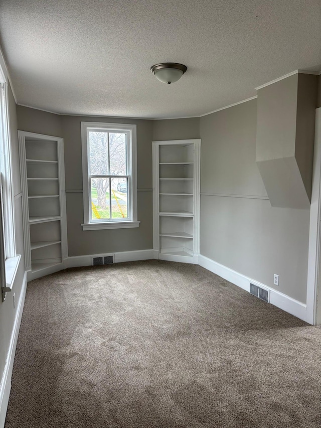 718 4th St N, Stillwater, MN 55082 - carpeted spare room with a textured ceiling, built in shelves, baseboards, and visible vents