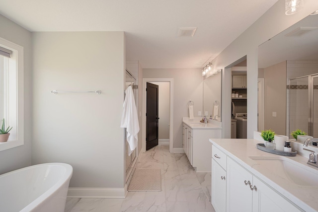 12816 Cedar Ridge Ln, Champlin, MN 55316 - full bath featuring a stall shower, marble finish floors, washer / clothes dryer, two vanities, and a freestanding bath