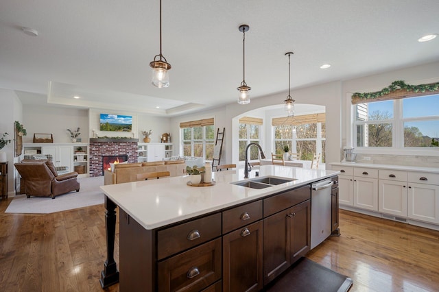 12816 Cedar Ridge Ln, Champlin, MN 55316 - kitchen with light countertops, wood finished floors, dishwasher, a center island with sink, and dark brown cabinetry