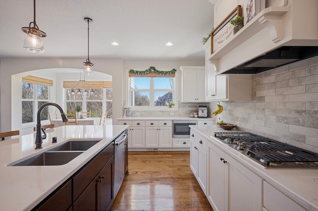 12816 Cedar Ridge Ln, Champlin, MN 55316 - kitchen featuring stainless steel appliances, ventilation hood, light countertops, decorative light fixtures, and white cabinetry